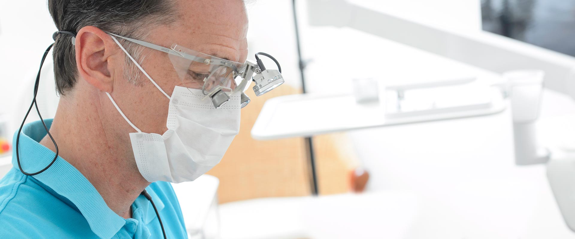 Dr. Liebetrau mit Mundschutz und Lupenbrille bei einer Wurzelbehandlung
