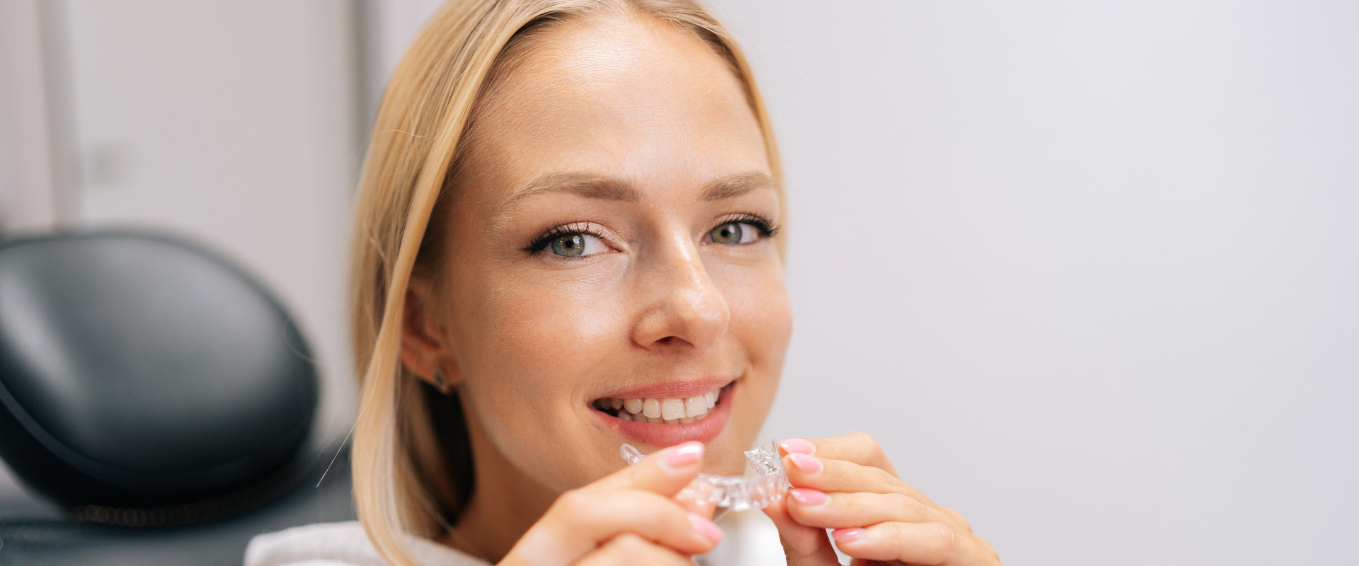 Junge Frau hält einen Aligner vor ihren Mund