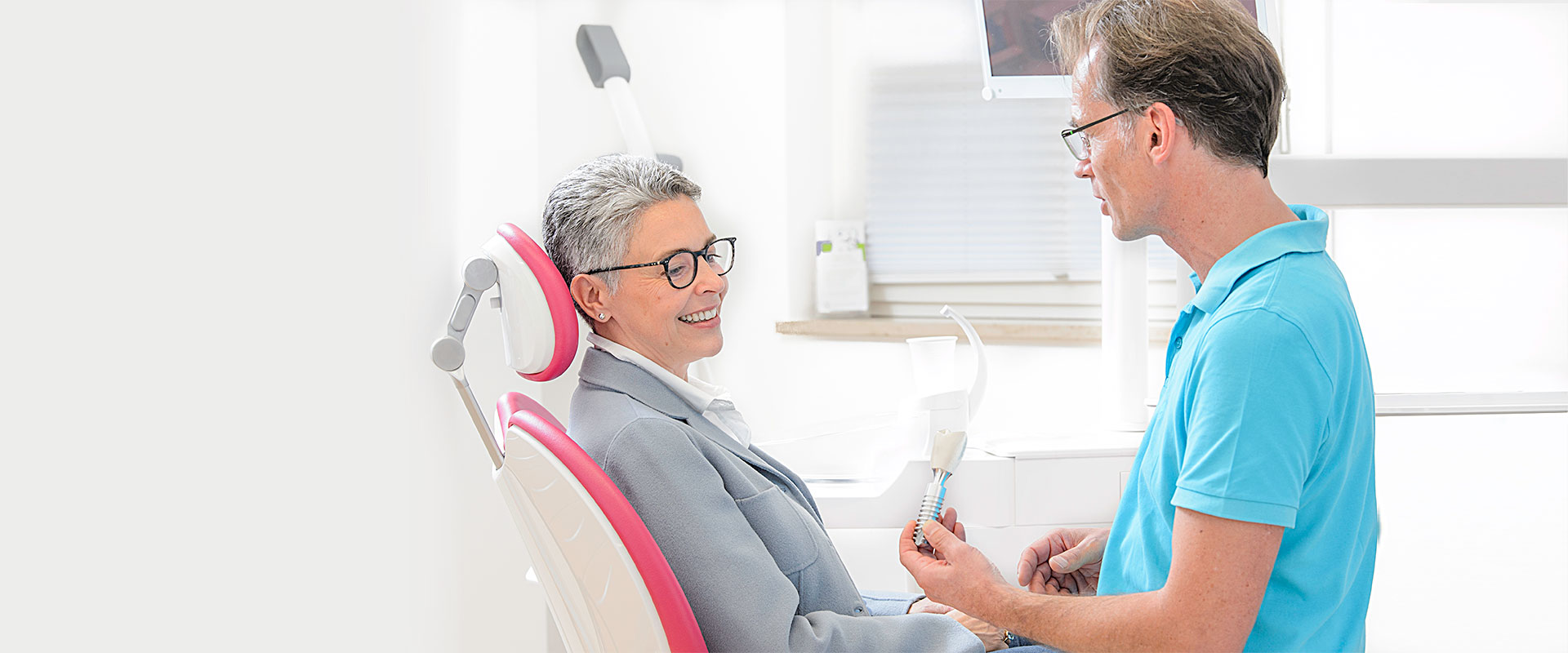 Dr. Liebetrau zeigt einer Patientin ein Modell eines Zahnimplantats